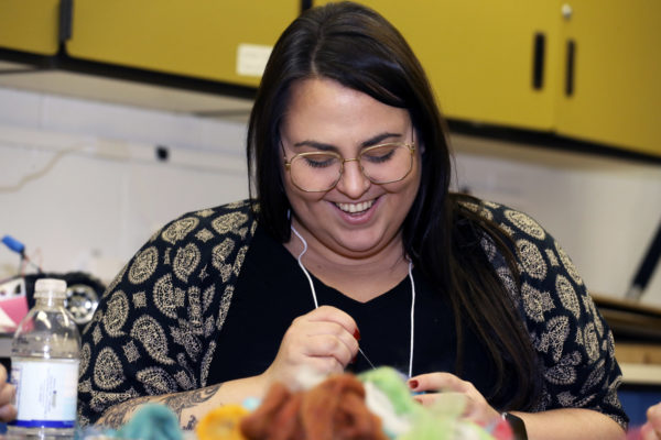 An educator smiles while working on a needle felting project.