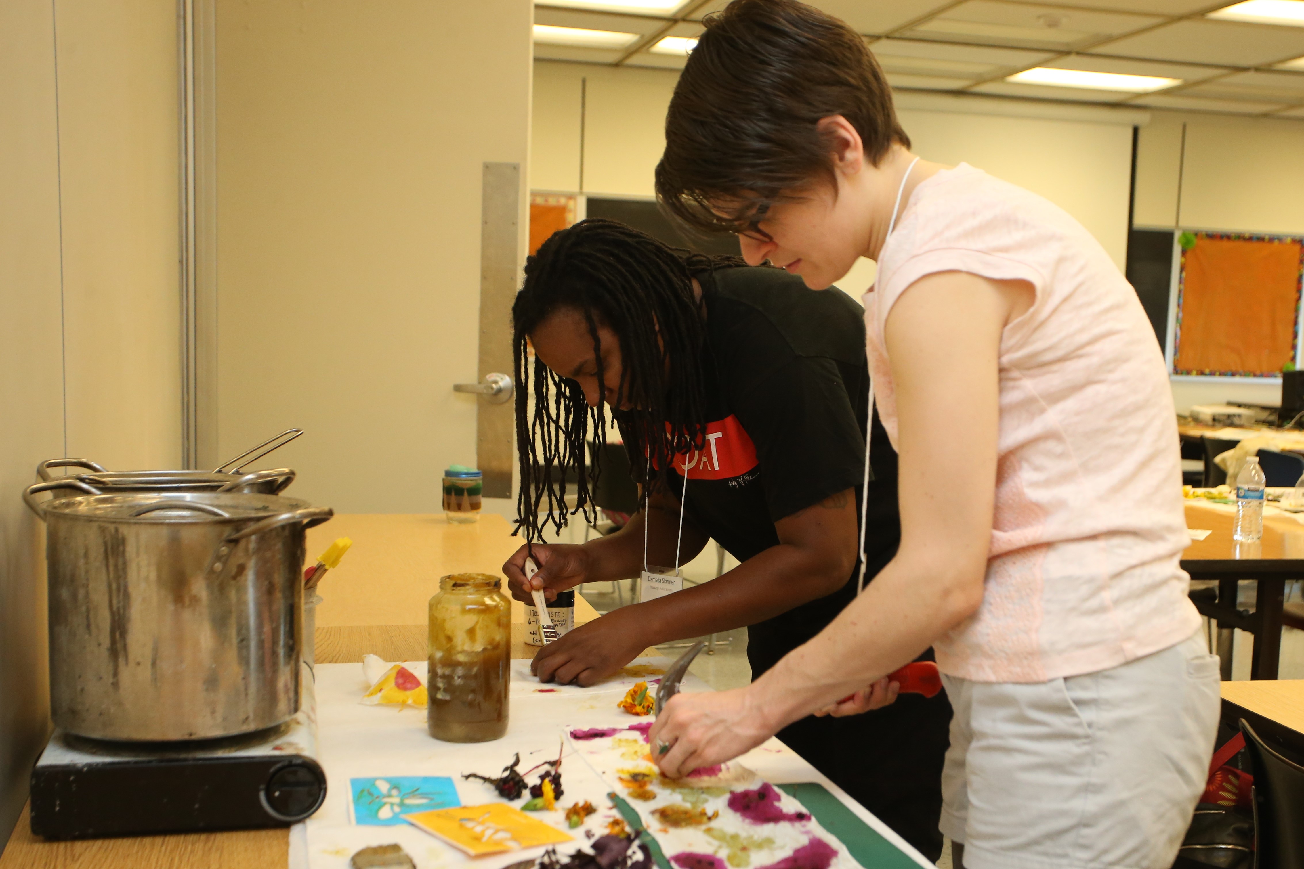 Two educators look closely at projects made using herbal plant dyes.