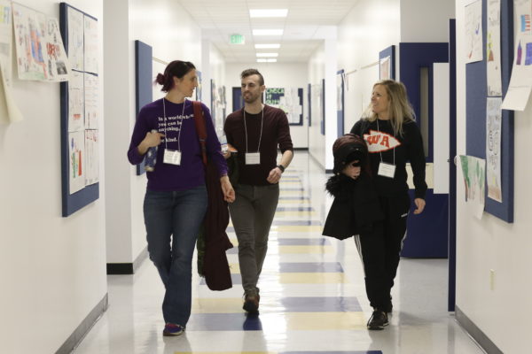 three adults walking down school hallway