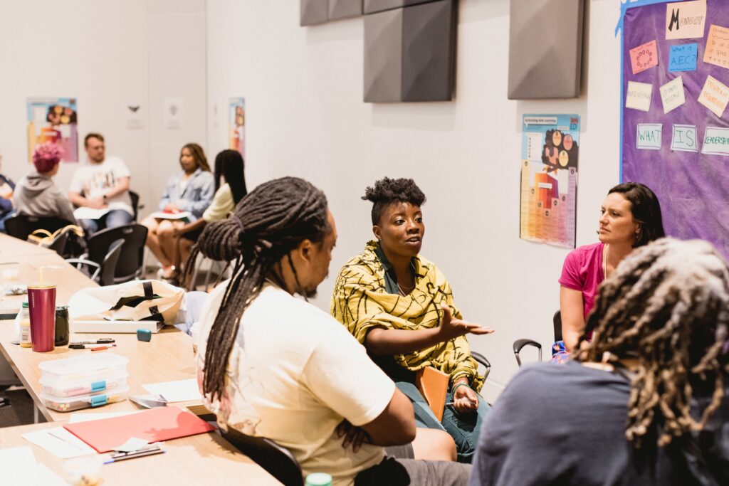 Two small groups of arts educators circle up during a workshop.