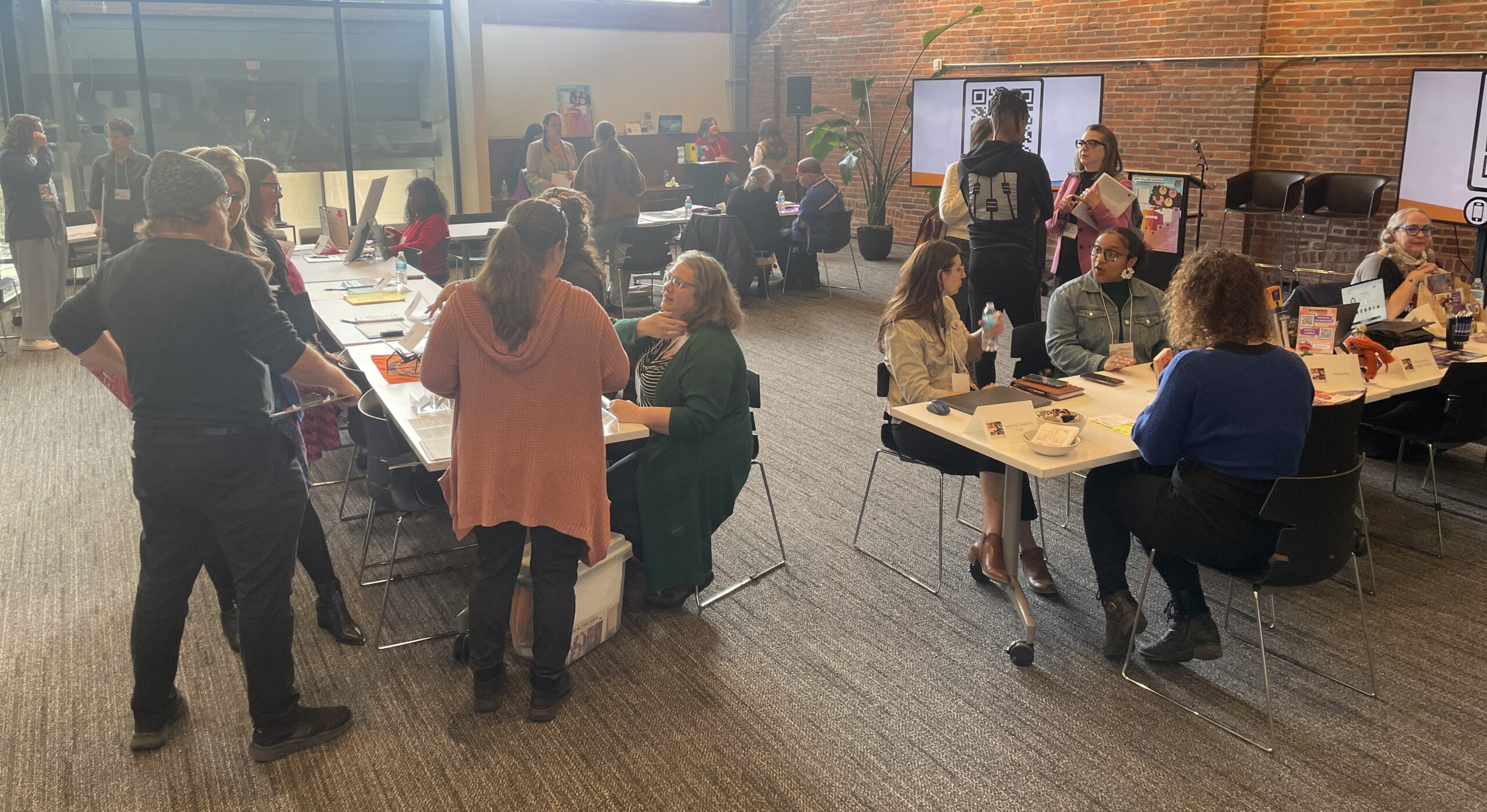 Room filled with arts partners seated at tables, interacting with educators