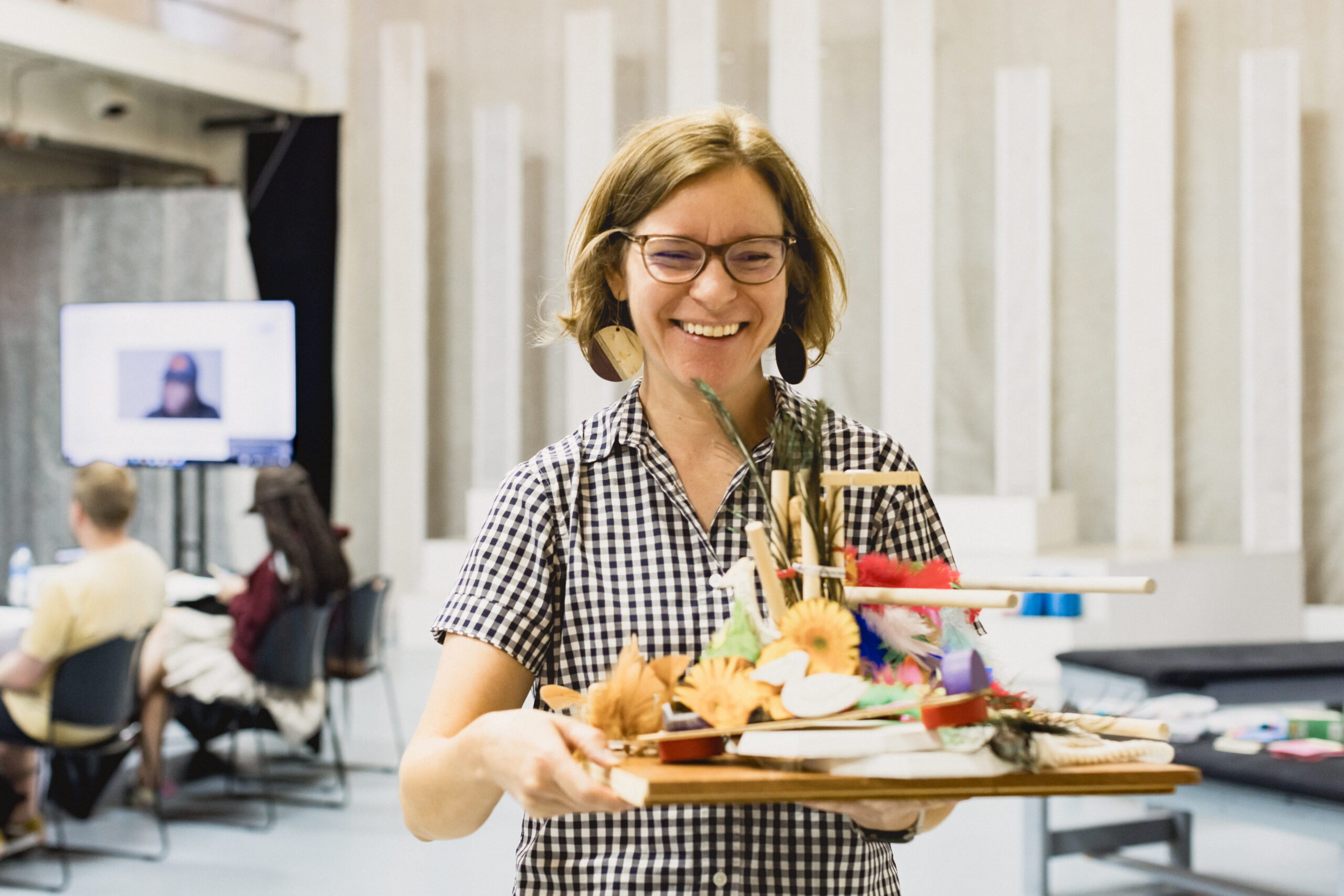 Smiling woman carries a tray of crafts.