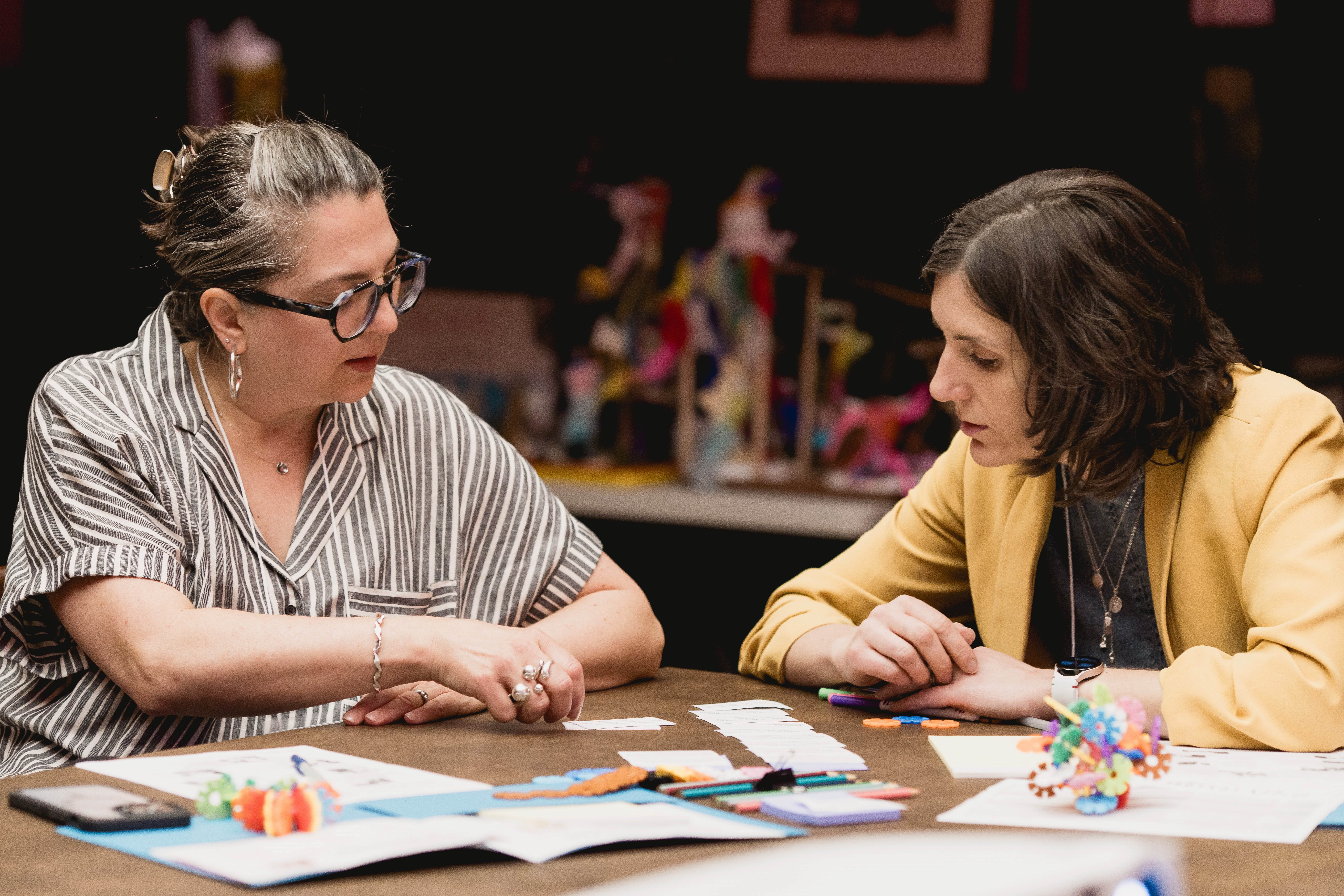 Two people sit and share arts learning resources